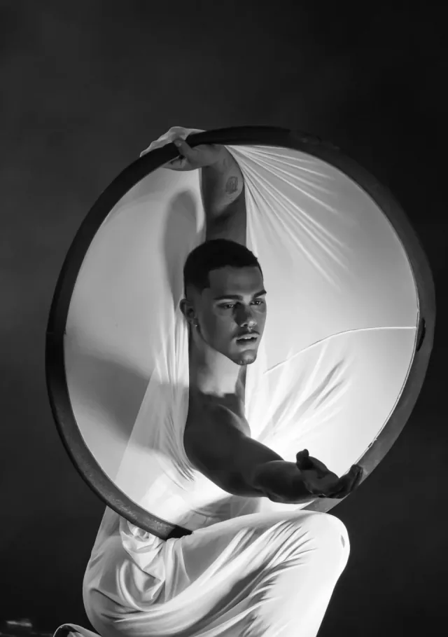 Male performer in glowing hoop — black and white