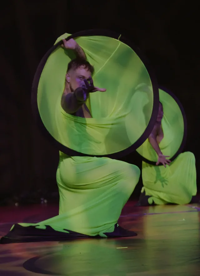 Neon green hoop dancers kneeling on stage