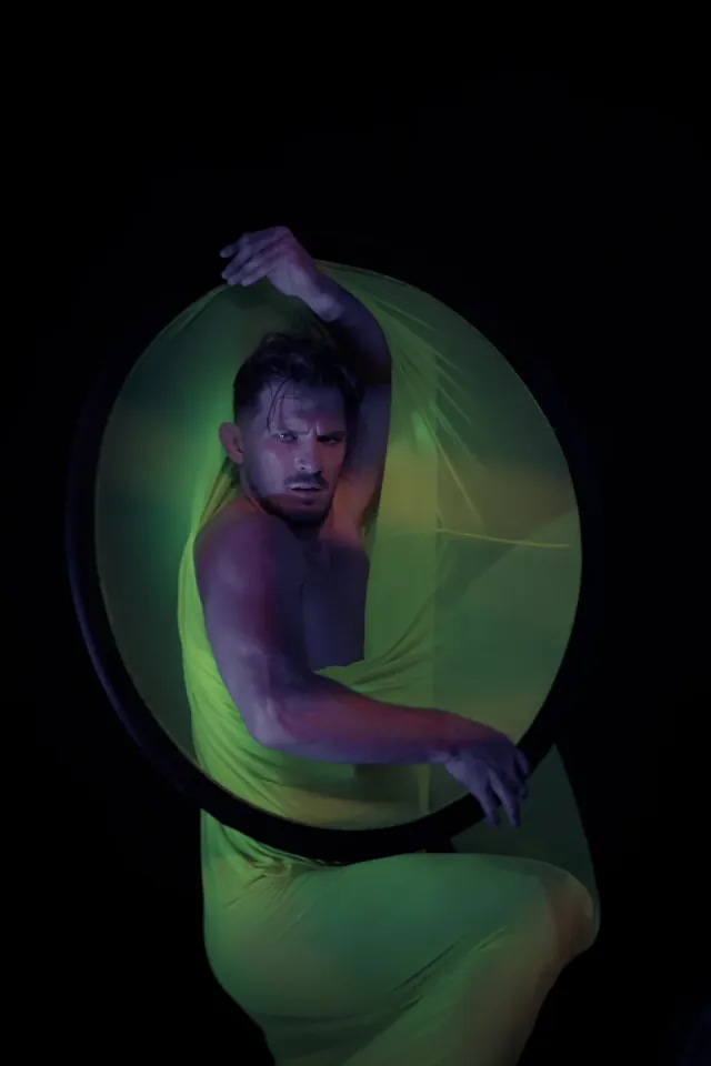 Male aerialist in lyra with green fabric